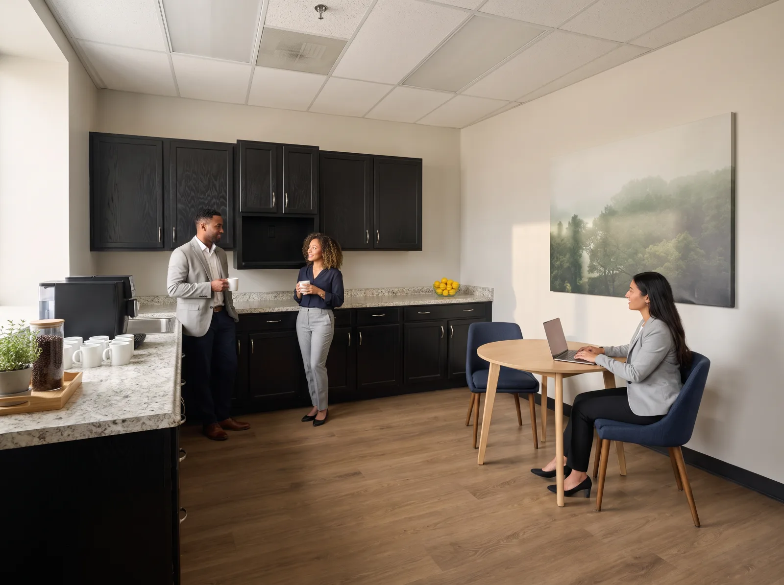 Staged photo of the members' break room: black cabinets, stone-look counters, a coffee station and two people talking over coffee