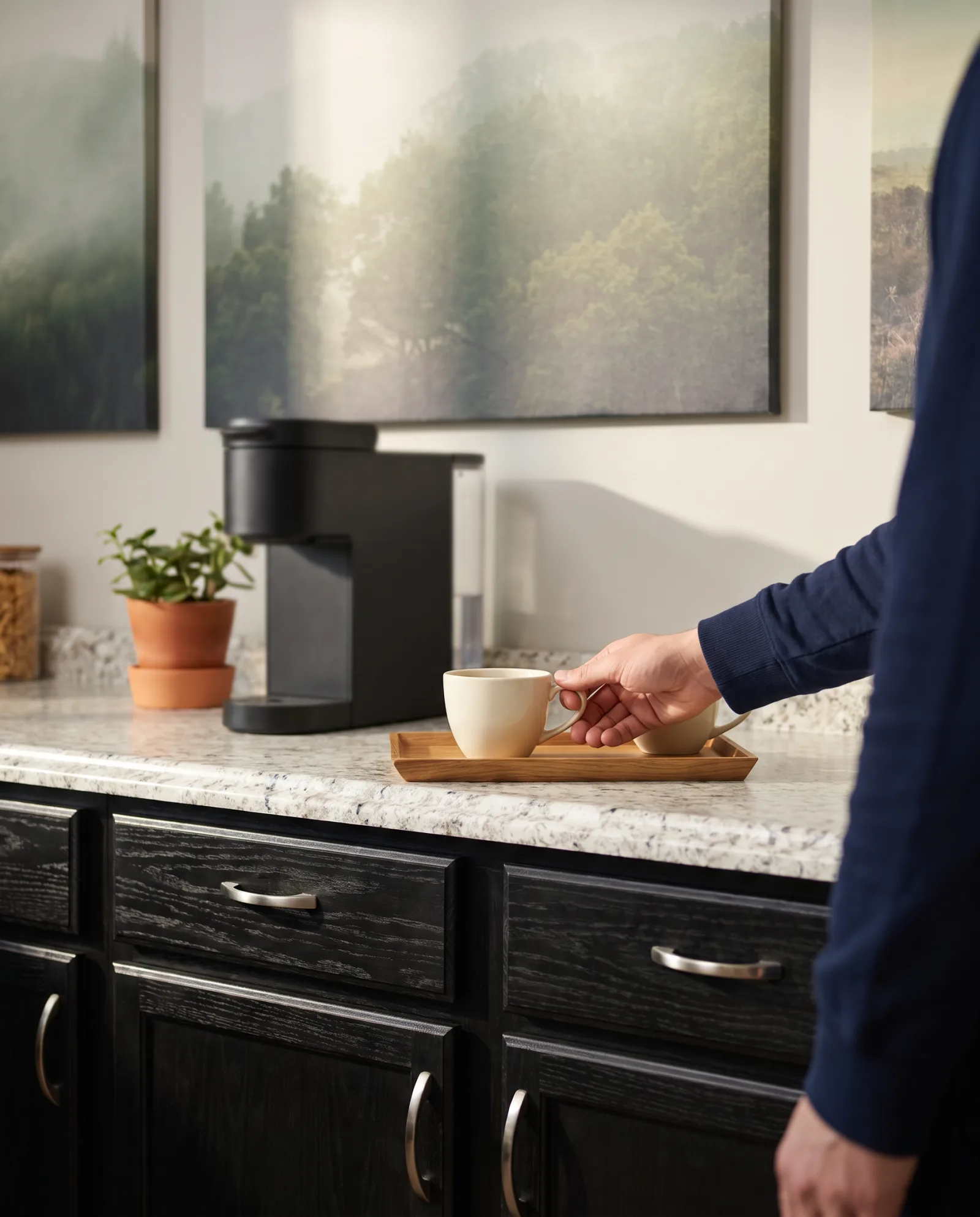 Staged photo: two cups of coffee set on a stone-look counter beside black cabinets